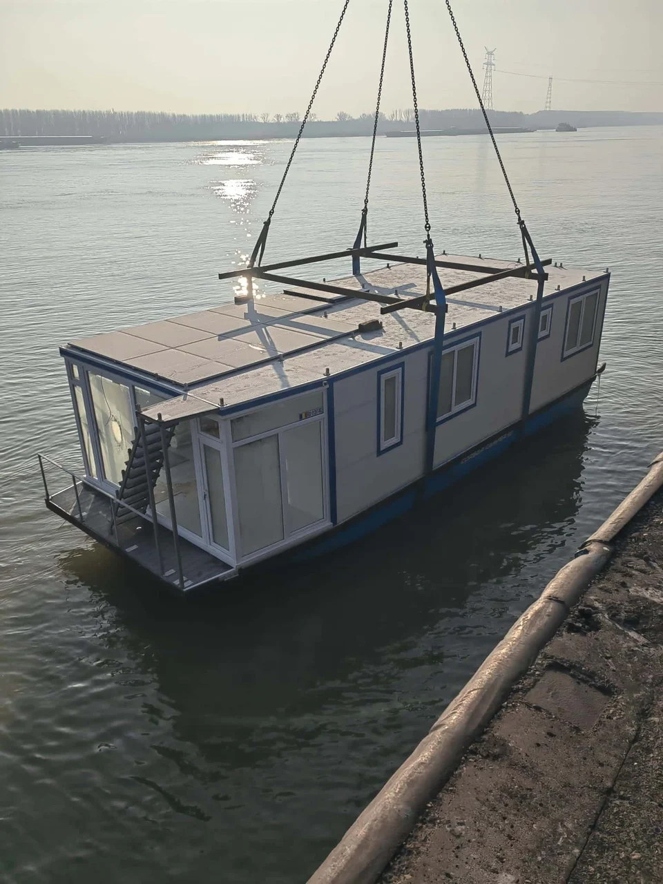 Houseboat suspendat cu macara deasupra apei
