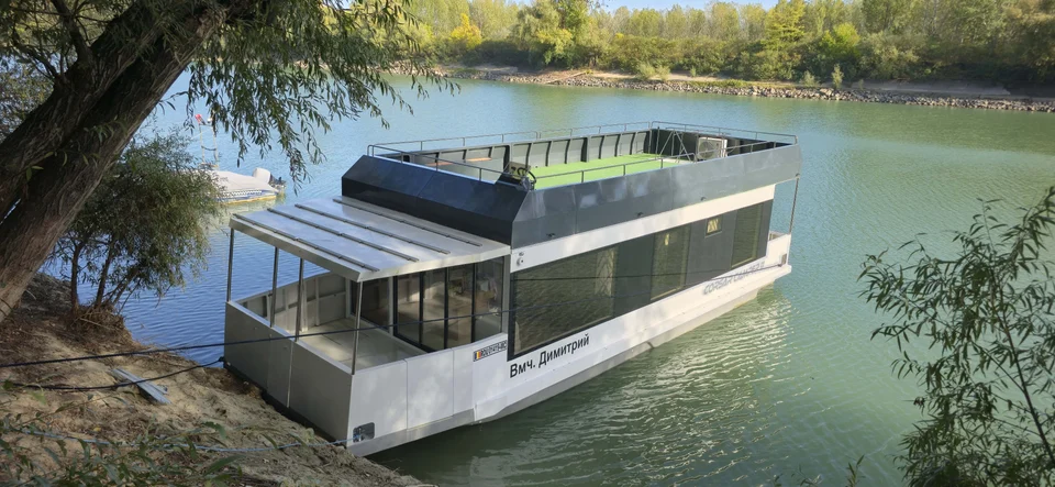 Houseboat cu terasă, acostat lângă mal