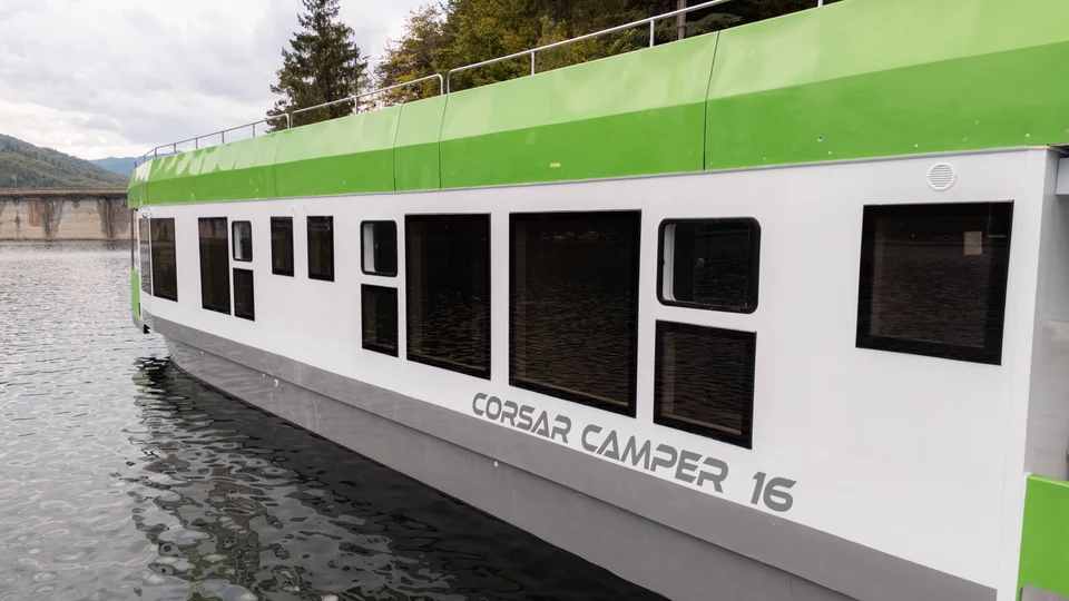 Houseboat alb și verde pe apă, vedere laterală