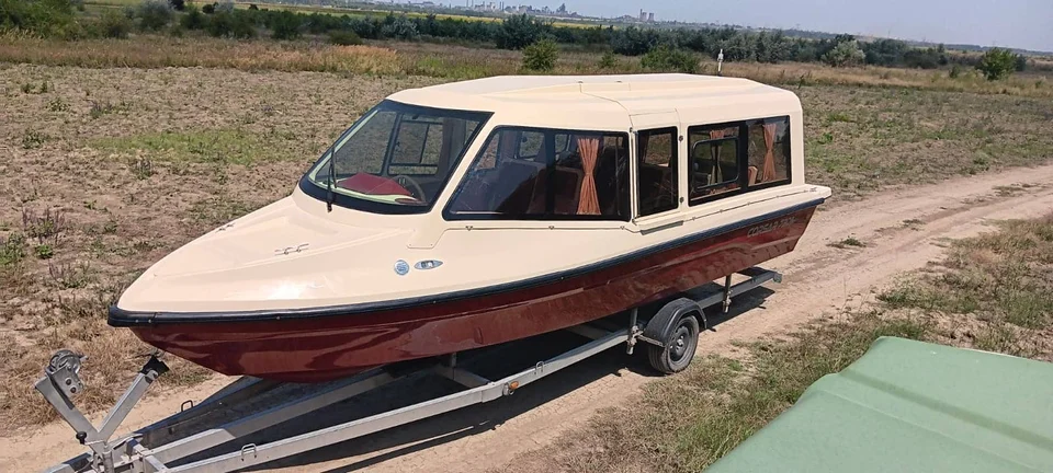 Barcă vișinie și crem cu cabină, vedere din față pe remorcă