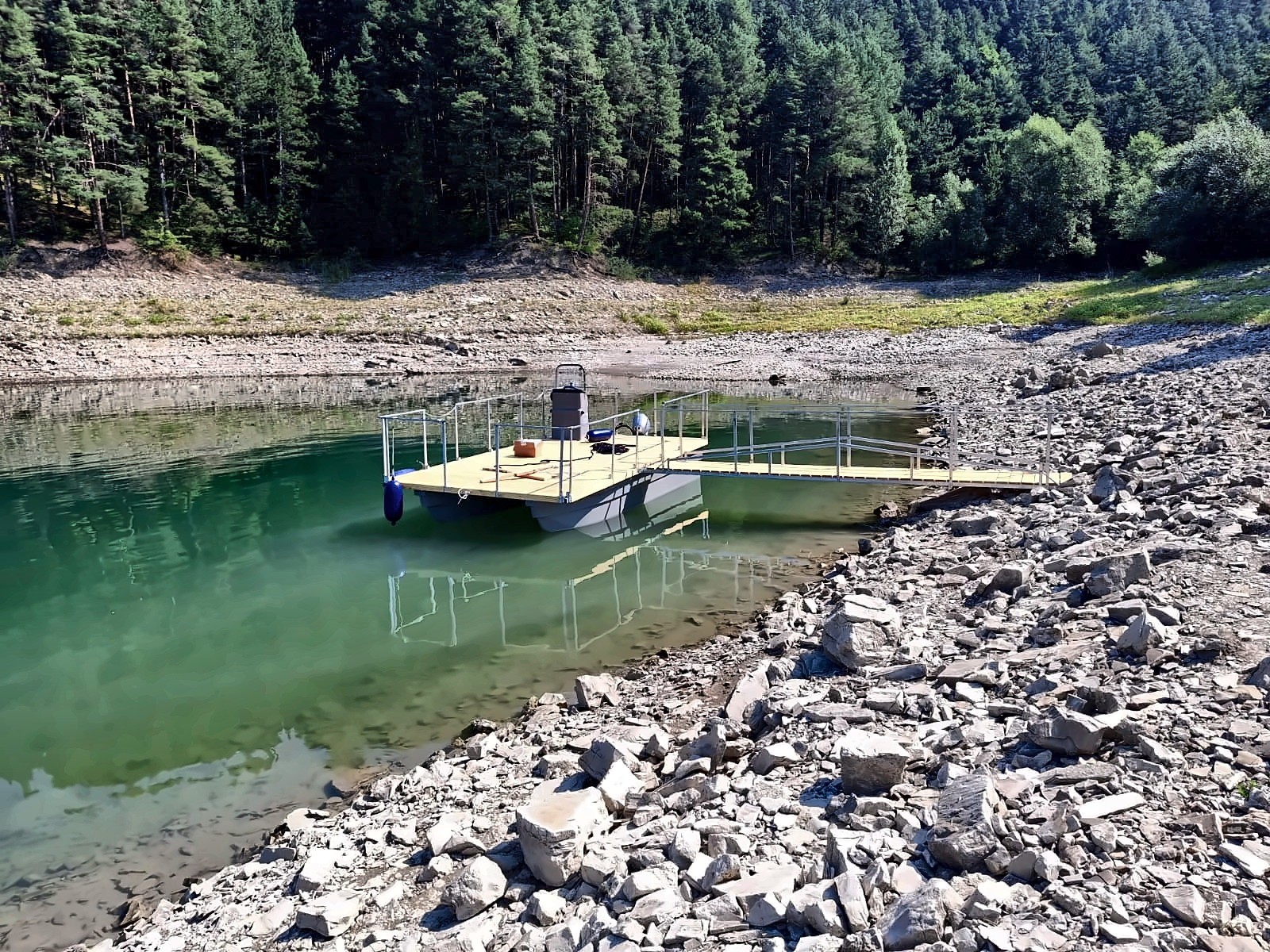 Catamaran cu punte deschisă pe lac, lângă mal